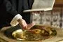præst med bibel i dene ene hånd og den anden i døbefont