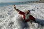 Denne franske julemands jul bliver hvid af skumsprøjt i bølgen blå Foto: AP/Lionel Cironneau / POLFOTO