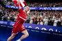 Viktor Axelsen i rødt tøj løber med det danske flag efter OL-sejr