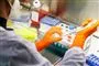 Et laboratorium hvor en medarbejder med gummihandsker sidder med nogle pipetter