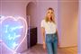 Kvinde poserer foran hjerte af neon