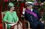 Prinsesse Claire i grøn spadseredragt sidder ved siden af prins Laurent, der har fuld uniform og lilla skærf på
