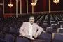 en mand i lyserød habit i en teatersal