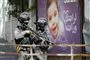 Kampklædt soldat står foran en plakat med et barn