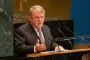 Løkke Rasmussen sidder bag et bord med en mikrofon foran sig og gestikulere med den ene hånd