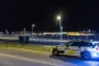 Politifolk og en politbil foran pigtrådshegn ind til lufthavnen