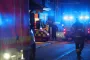 Røde brandbiler holder foran en bygning, mens blå blink lyser op i den mørke baggrund