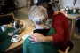 En ældre dame sidder ved et kaffebord med ryggen til kameraet. En anden dame holder hende om skulderen