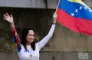Kvinde i hvidt tøj flager med det venezuelanske flag og vinker 
