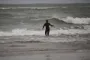 En enlig surfer står med ryggen til på vej ud mod store bølger.
