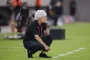 fodboldtræner sidder på hug på sidelinien