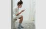 kvinde sidder på toilet med mobiltelefon