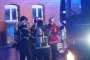 Tre brandfolk og en indsatsleder står foran rød bygning