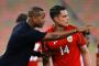 Kluivert står i sort t-shirt og taler med en spiller i rød trøje