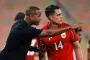 Kluivert står i sort t-shirt og taler med en spiller i rød trøje