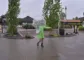 Kvinde i grøn regnjakke danser under en gennemsigtig paraply