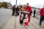 kvinde i rød frakke hænger plakat op