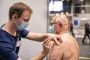 Mand med maske vaccinerer person