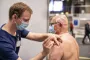 Mand med maske vaccinerer person