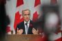 Mark Carney står på talerstol foran canadisk flag