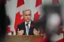 Mark Carney står på talerstol foran canadisk flag