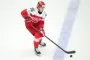 Nick Olesen i rødt og hvidt på skøjter med pucken foran sig