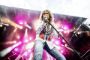 David Coverdale let bøjet over mikrofon på en oplyst scene.