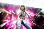 David Coverdale let bøjet over mikrofon på en oplyst scene.