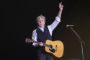 Paul McCartney på en scene med guitar om halsen og arm i vejret