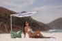 en kvinde i bikini under en parasol