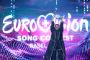 en sortklædt person holder noget i vejret på eurovisionscenen