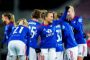 Blåklædte fodboldspillere står i en kreds