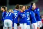 Blåklædte fodboldspillere står i en kreds