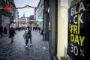 gående på gade med Black Friday-skilte i vinduerne