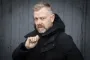 Casper Christensen i vinterjakke med højre hånd ved kraven