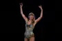 Taylor Swift i sølvkjole og armene over hovedet under en koncert