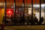 En masse uniformerede betjente sidder bag store vinduer