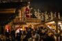 En masse mennesker foran en udsmykket træhytte, hvor julemanden står på en altan