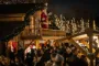 En masse mennesker foran en udsmykket træhytte, hvor julemanden står på en altan
