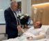 en mand i en hospitalsseng og en minister ved siden af