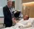 en mand i en hospitalsseng og en minister ved siden af