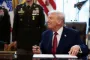 TRump sidder ved skrivebord og smiler mærkeligt til siden