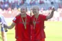 To kvinder i røde trøjer holder om hinanden med medaljer om halsen