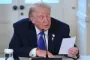 TRump sidder og læser et papir