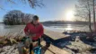 en person står ved en sø i klart vejr med sol