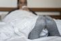 Person med uldne sokker ligger under dyne