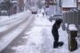 en snefyldt vej og en person der skovler sne