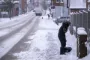 en snefyldt vej og en person der skovler sne