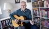 en mand sidder med en guitar