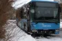 En blå bus holder i sneen med smadret forende